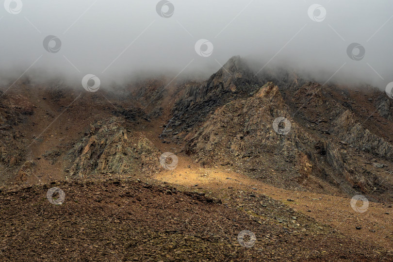 Скачать Ужасные горные тени. Драматический туман среди гигантских скалистых гор. Призрачный атмосферный вид на большой утес. Низкие облака и красивые скалистые горы. Минималистичный пейзаж таинственного места. фотосток Ozero
