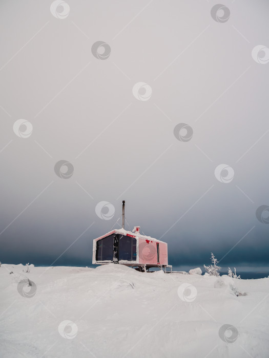 Скачать Вертикальный минималистичный фон с изображением одинокой красной хижины зимой. Дубладом на горе Володяная Кандалакша, Мурманская область в России. фотосток Ozero