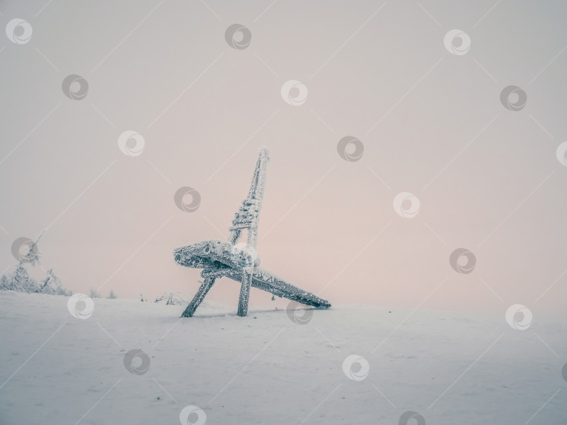 Скачать Минималистичный зимний фон с замерзшим деревянным стулом в морозной дымке на фоне розового неба полярного дня. фотосток Ozero