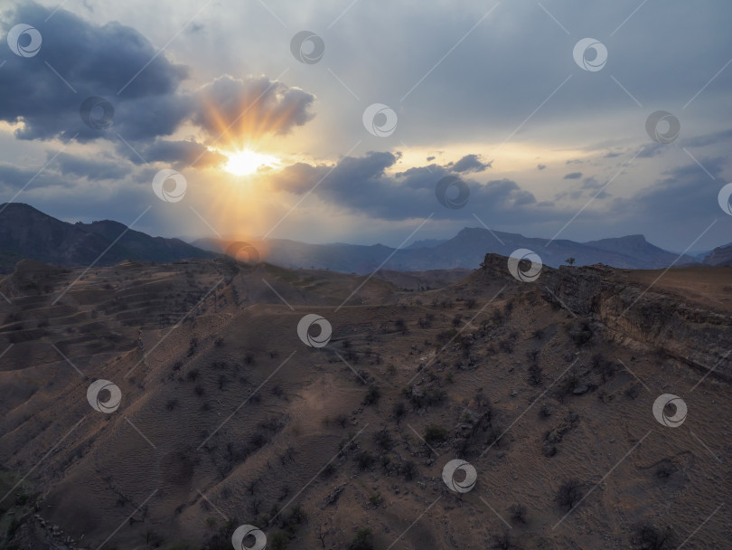 Скачать Яркие последние лучи заходящего солнца над гористым пустынным плато. фотосток Ozero