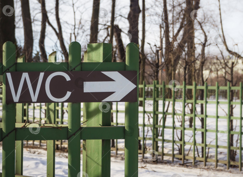 Скачать Вывеска туалета WC на зеленом заборе в общественном месте. Наружная вывеска. фотосток Ozero