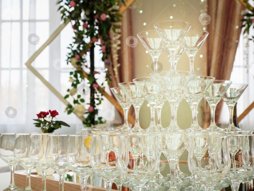 Скачать Крупным планом пустые бокалы для вина на столе представляют собой пирамиду. Красивая свадебная церемония в закрытом помещении. фотосток Ozero