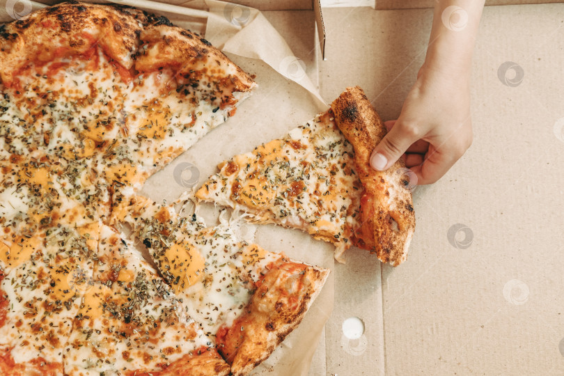 Скачать Доставка пиццы. Итальянская пицца. рука держит кусок пиццы. онлайн-доставка еды. фаст-фуд на столе фотосток Ozero