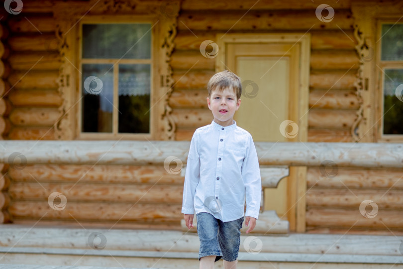 Скачать мальчик прогуливается возле дома. Ребенок на сцене. мальчик на фоне деревянного дома. Мальчик в белой рубашке фотосток Ozero