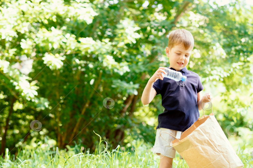 Скачать Концепция сохранения окружающей среды, маленький мальчик собирает мусор и пластиковые бутылки на пляже, чтобы выбросить их в мусорное ведро фотосток Ozero