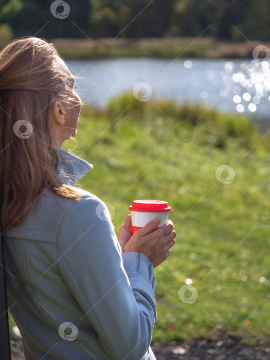 Скачать Многоразовая кофейная чашка в руках женщины в осеннем парке. фотосток Ozero