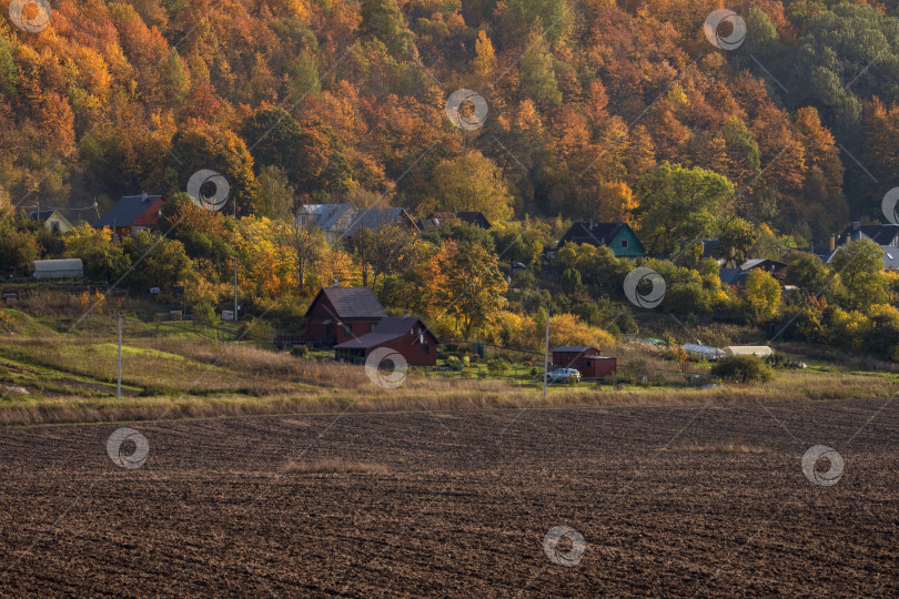 Скачать Пейзаж с сельскохозяйственными угодьями, готовыми к посадке, с деревней на холме на заднем плане. фотосток Ozero