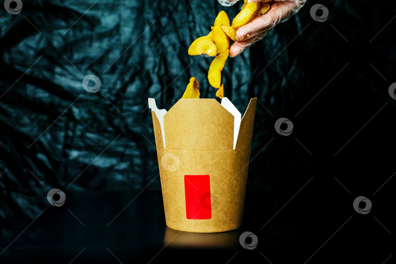 Скачать Картофель фри, летящий в картонной коробке на темном фоне фотосток Ozero