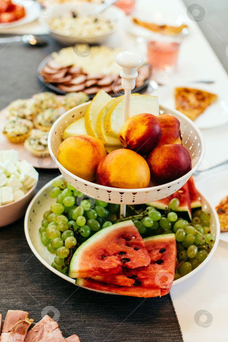 Скачать Тарелка с разными фруктами на праздничном столе вертикальная фотосток Ozero