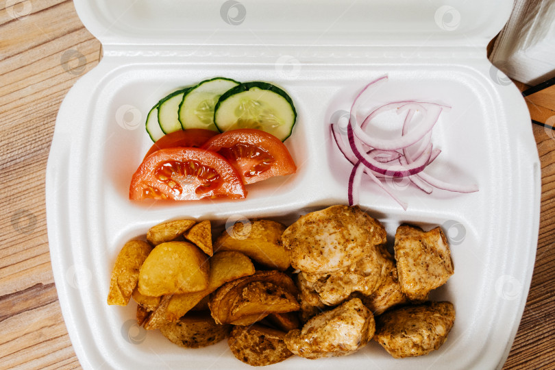 Скачать Блюдо из мяса, картофеля фри и овощей в пластиковом контейнере фотосток Ozero