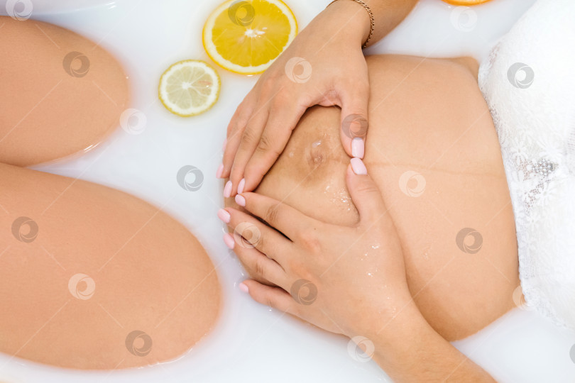 Скачать Беременная девушка в ванне с молоком и цитрусовыми крупным планом фотосток Ozero