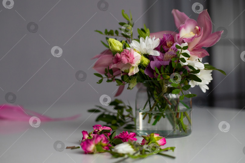Скачать Цветы в стеклянной вазе на белом столе. Букет из альстромерий, орхидей, роз, хризантем. Составление букета. фотосток Ozero