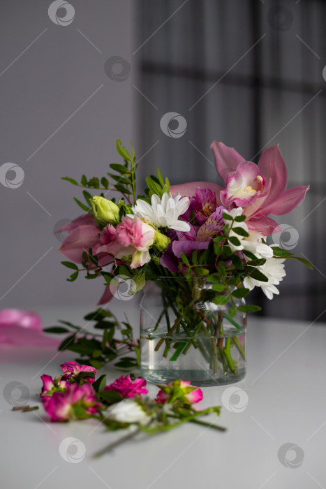 Скачать Цветы в стеклянной вазе на белом столе. Букет из альстромерий, орхидей, роз, хризантем. Составление букета. фотосток Ozero