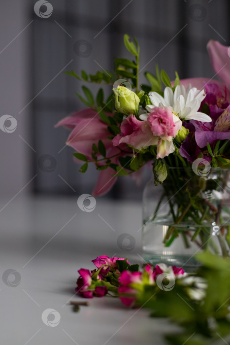 Скачать Цветы в стеклянной вазе на белом столе. Букет из альстромерий, орхидей, роз и белых хризантем. Составление букета. Размытый внутренний фон. Современный скандинавский интерьер фотосток Ozero