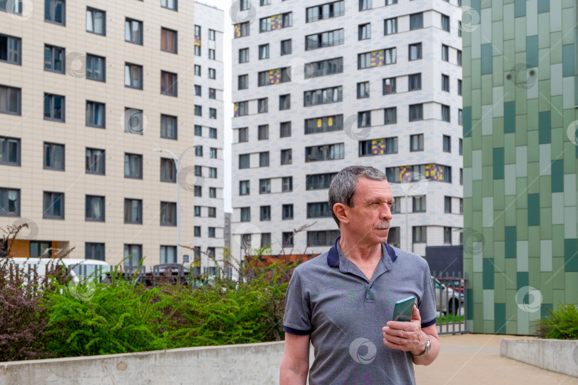 Скачать Взрослый кавказский мужчина стоит и держит смартфон фотосток Ozero