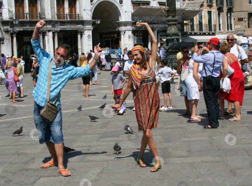 Скачать ВЕНЕЦИЯ, ИТАЛИЯ - 22 августа 2008 года: Множество туристов на площади, девушка танцует с местным итальянцем, туристы фотографируют достопримечательности города, дети кормят голубей фотосток Ozero