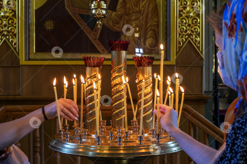 Скачать Две женщины молитвенно зажигают свечи у древней чудотворной иконы фотосток Ozero