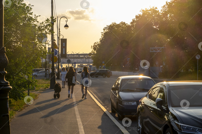 Скачать Прохожие прогуливаются по улице летним вечером на закате. фотосток Ozero