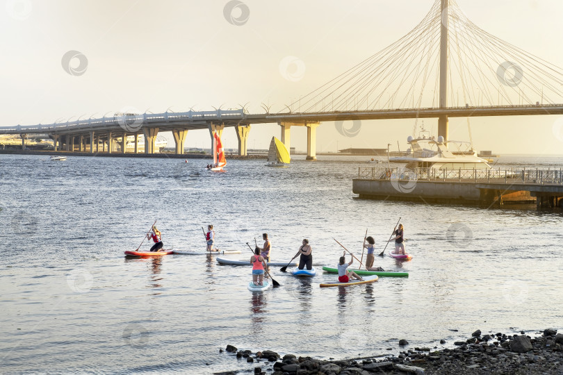 Скачать Вид на реку в городе с людьми, плавающими на стоячем весле. фотосток Ozero