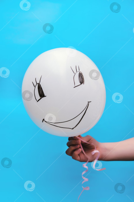 Скачать Белый воздушный шар на синем фоне. На шаре нарисована забавная рожица. фотосток Ozero