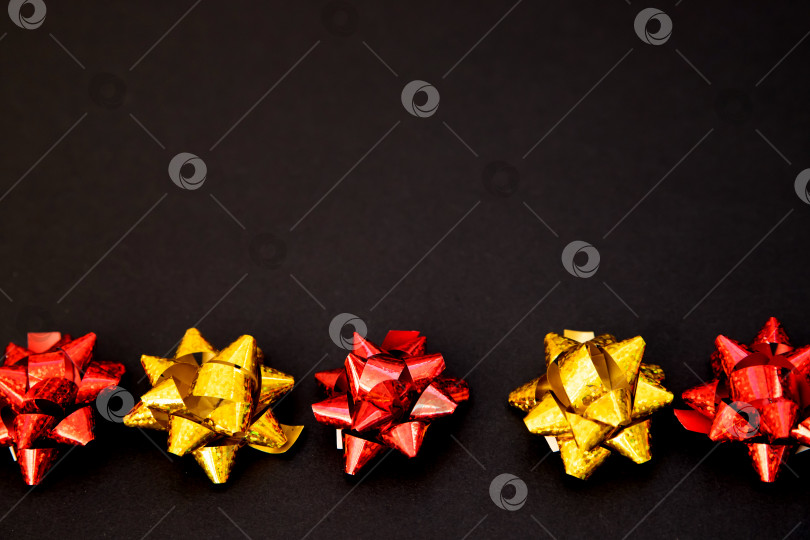 Скачать Подарочные банты лежат в линию на черном фоне.Рождество и Новый год.Подарок на день рождения. Стильный праздничный фон. фотосток Ozero
