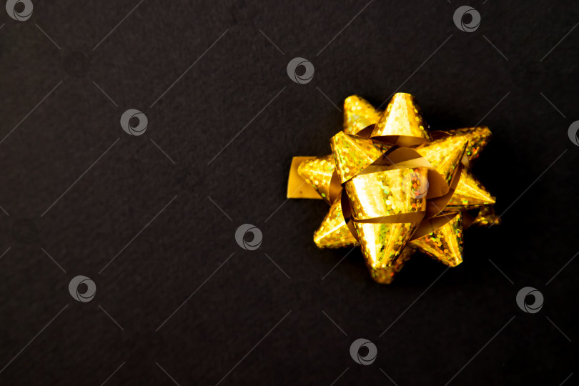 Скачать Подарочный бант золотистого цвета на черном фоне.Рождество и Новый год.Подарок на день рождения. фотосток Ozero