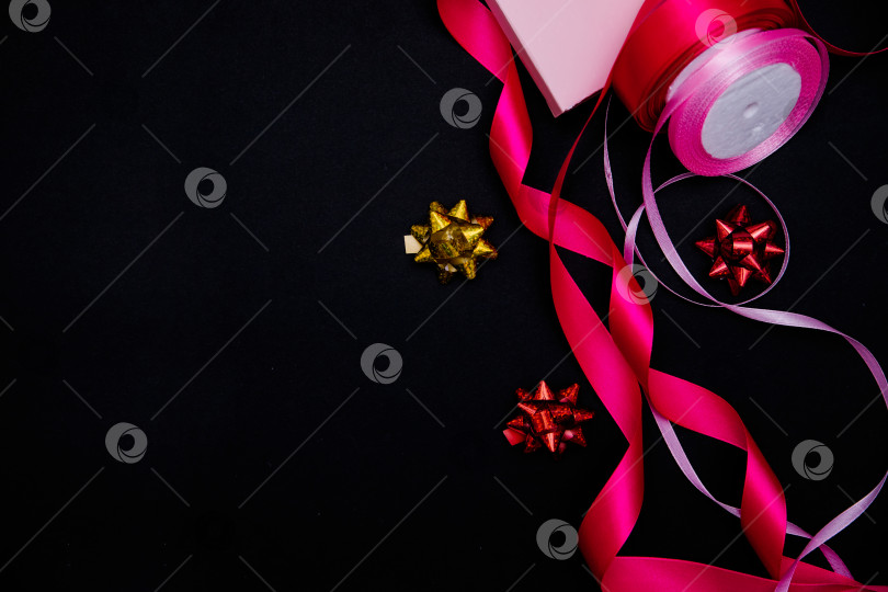 Скачать На черном фоне розовые атласные ленты и подарочные банты. Подарочная упаковка. фотосток Ozero