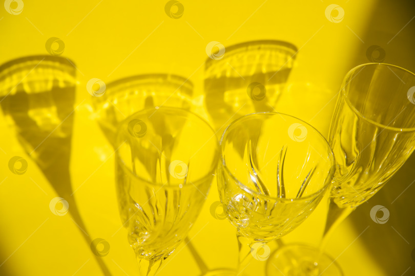 Скачать Пустые стаканы стоят на желтом фоне.Солнечный свет преломляется через стекло.Трендовые изображения. фотосток Ozero