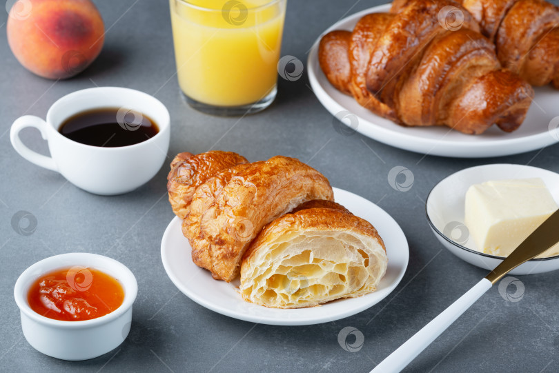 Скачать Свежеиспеченный французский круассан, кофе, масло и джем. Континентальный завтрак на сером столе фотосток Ozero