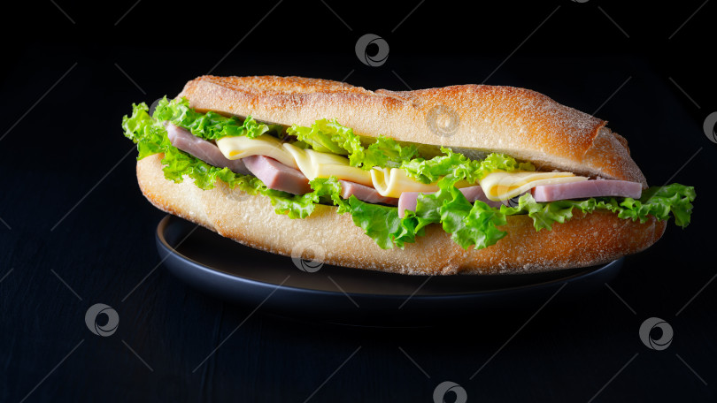 Скачать Бутерброд с багетом, выделенный на черном фоне фотосток Ozero