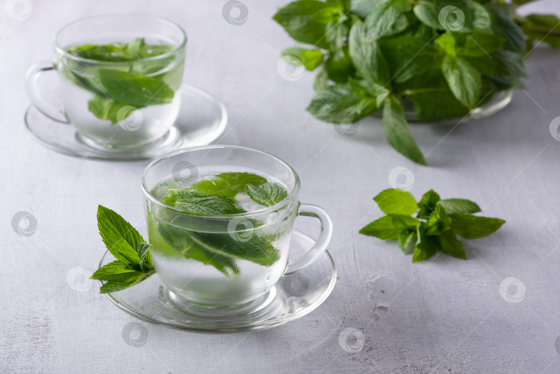 Скачать Мятный чай со льдом, освежающий травяной напиток в стакане со льдом и свежими листьями на темном фоне фотосток Ozero