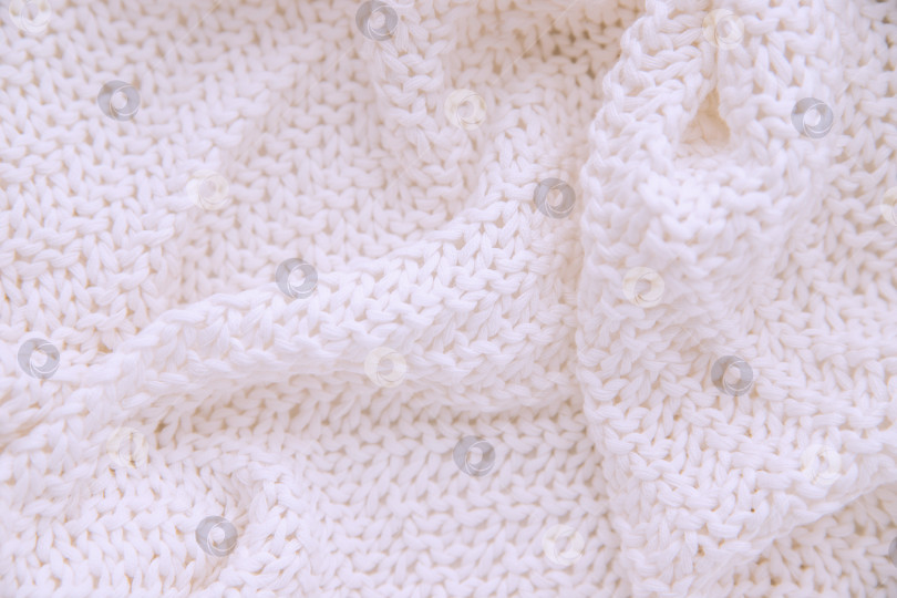 Скачать Теплое вязаное одеяло белого цвета крупным планом.Одеяло лежит неровными волнами. фотосток Ozero
