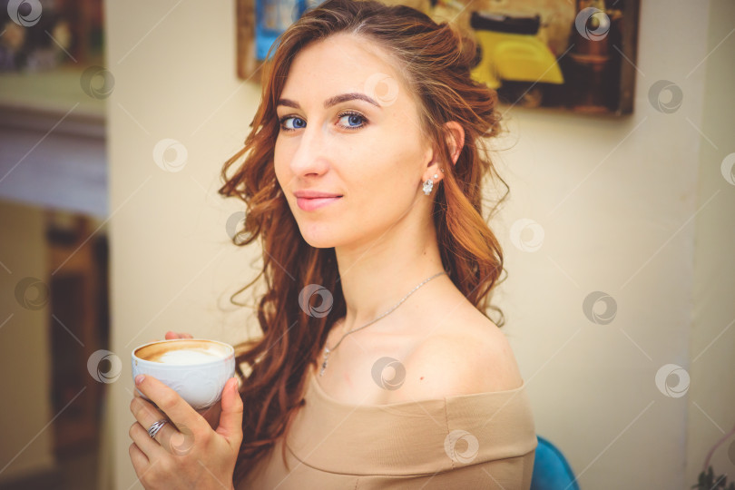 Скачать Портрет красивой женщины в кафе. Девушка улыбается и пьет горячий напиток. фотосток Ozero