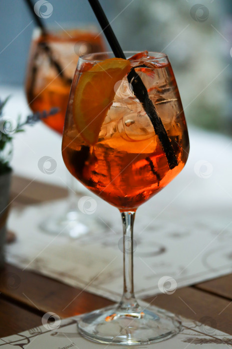 Скачать Два бокала апельсинового коктейля aperol spritz или campari с долькой апельсина и льдом на столе в ресторане. Концепция праздника. Живое фото с бокалом летнего коктейля в отпуске фотосток Ozero