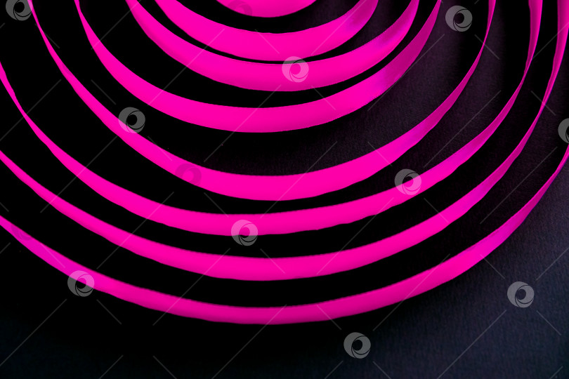 Скачать Розовая атласная лента расположена спиралевидными кругами на черном фоне. Абстрактный фон. фотосток Ozero