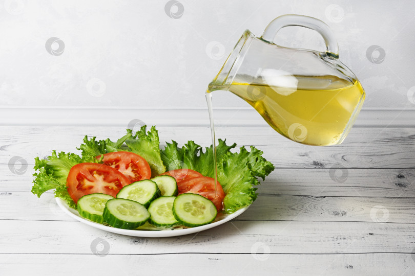 Скачать Овощной салат с оливковым маслом. Свежая смесь помидоров, огурцов и зеленого салата с растительным маслом в режиме левитации фотосток Ozero