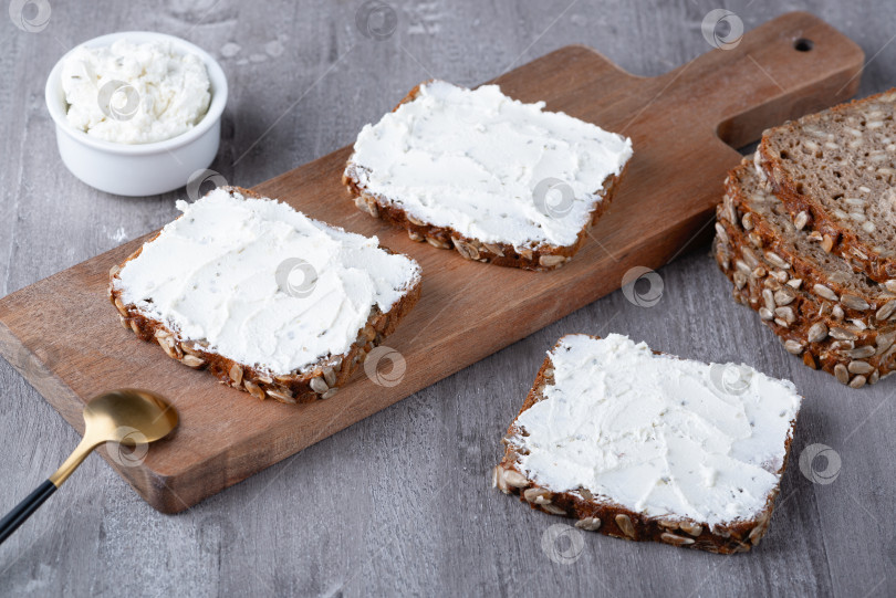 Скачать Ржаной хлеб со сливочным сыром на сером столе фотосток Ozero