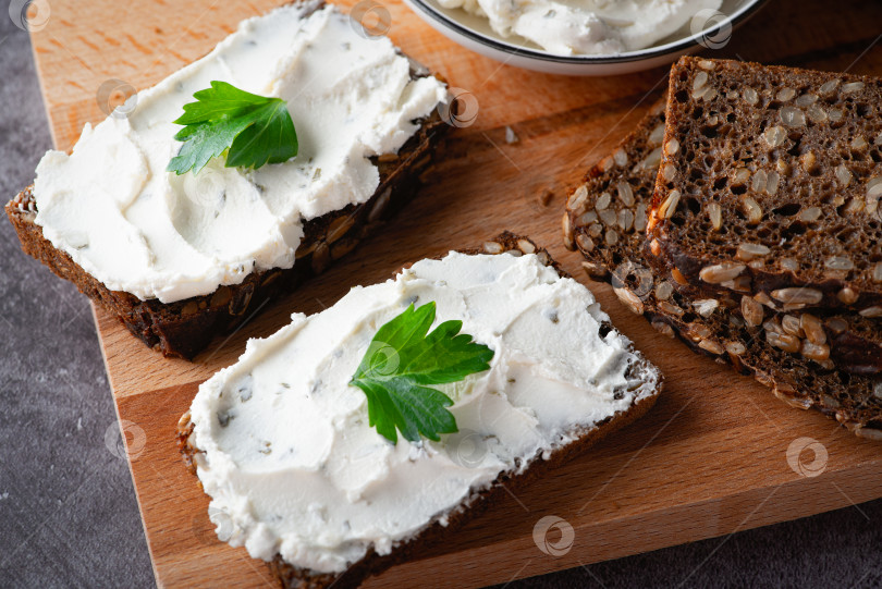 Скачать Ржаной хлеб со сливочным сыром на сером столе. Цельнозерновой ржаной хлеб с семенами фотосток Ozero