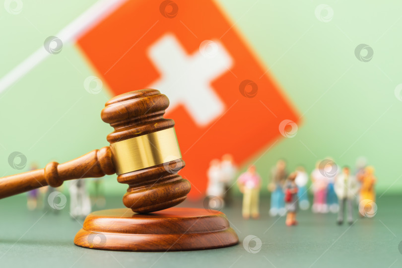 Скачать Деревянный молоток судьи, флаг и игрушечные человечки из пластика на цветном фоне - концепция судебных процессов в швейцарском обществе фотосток Ozero