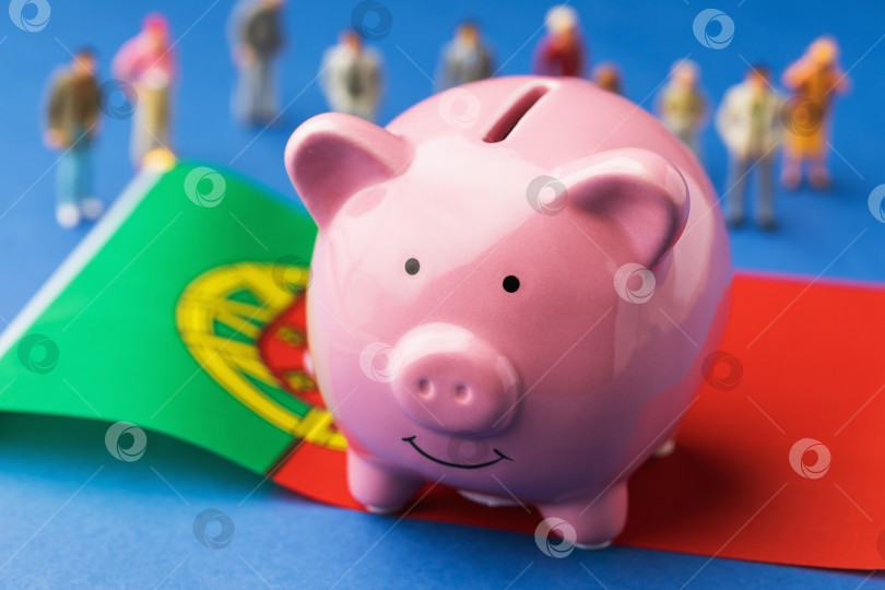 Скачать Копилка, португальский флаг и пластиковые игрушечные человечки на цветном фоне, концепт на тему доходов населения Португалии фотосток Ozero