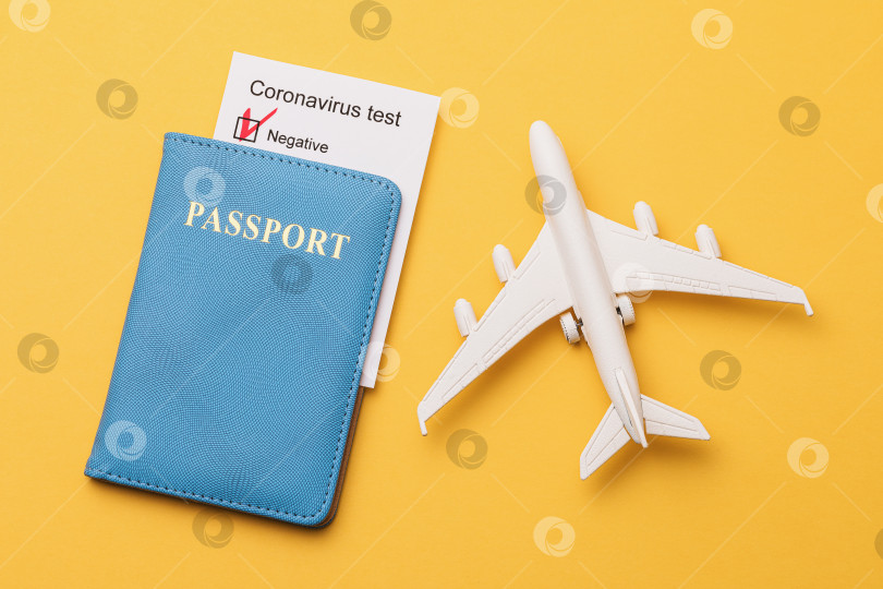 Скачать Паспорт, отрицательный результат теста на коронавирус и игрушечный самолет на желтом фоне, концепция разрешения авиаперелетов во время пандемии фотосток Ozero