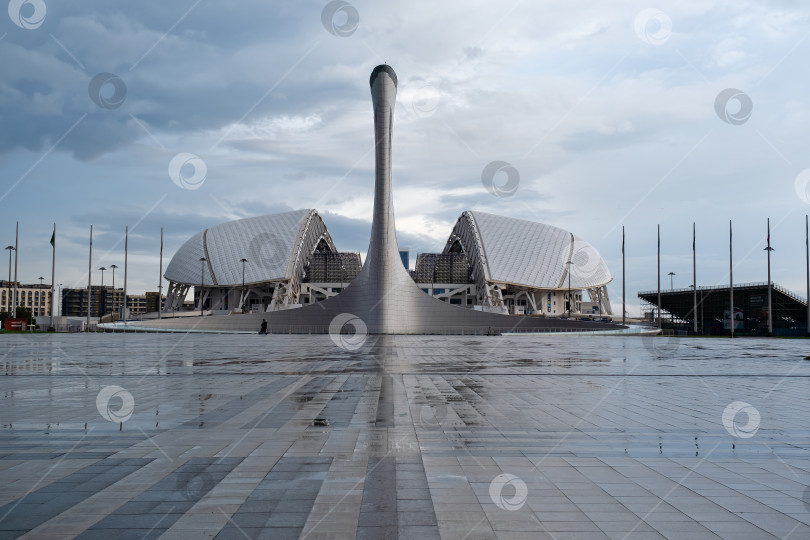 Скачать СОЧИ, АДЛЕР, РОССИЯ, 13 апреля 2023 года: Олимпийский факел и стадион "Фишт" в Олимпийском парке, вид спереди фотосток Ozero