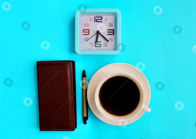 Скачать Чашка кофе, блокнот, будильник и ручка на синем фоне. Макет на тему бизнеса. фотосток Ozero