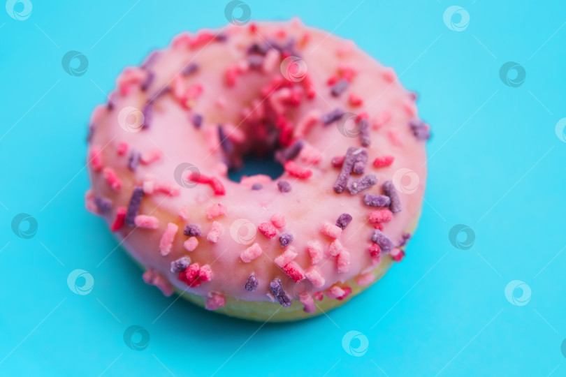 Скачать Один розовый пончик на синем фоне. Сладкая закуска. фотосток Ozero