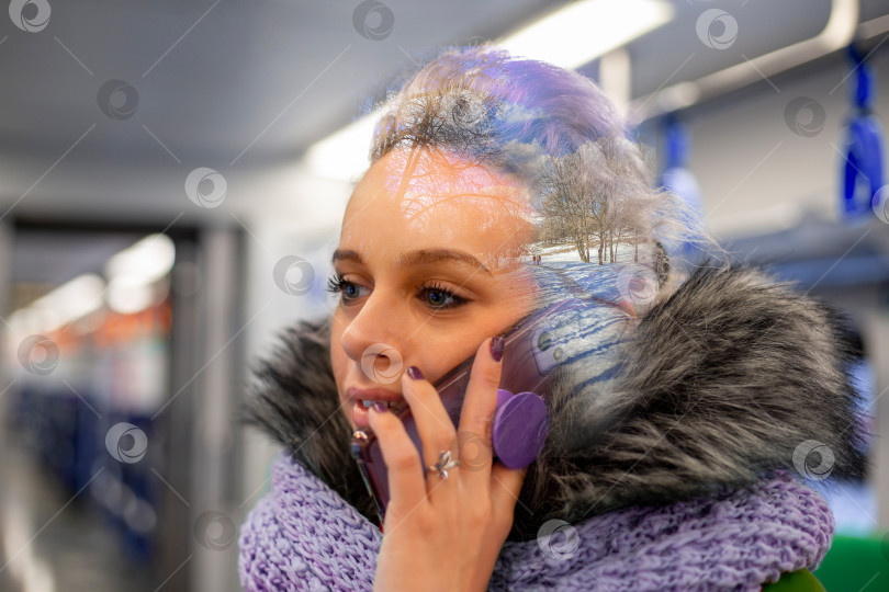Скачать Молодая женщина в зимней одежде с меховым воротником разговаривает по телефону в метро. Портрет крупным планом фотосток Ozero