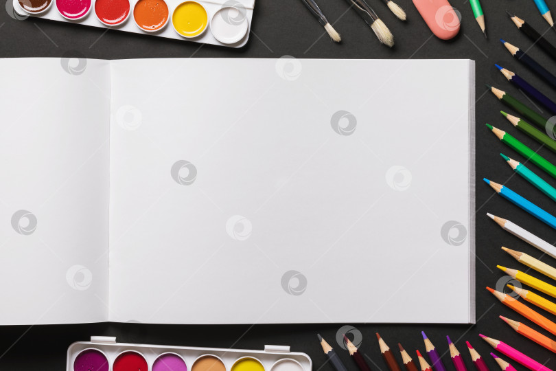 Скачать Открытый чистый альбом для рисования, акварельные краски, кисти и цветные карандаши на темном фоне с копией space фотосток Ozero