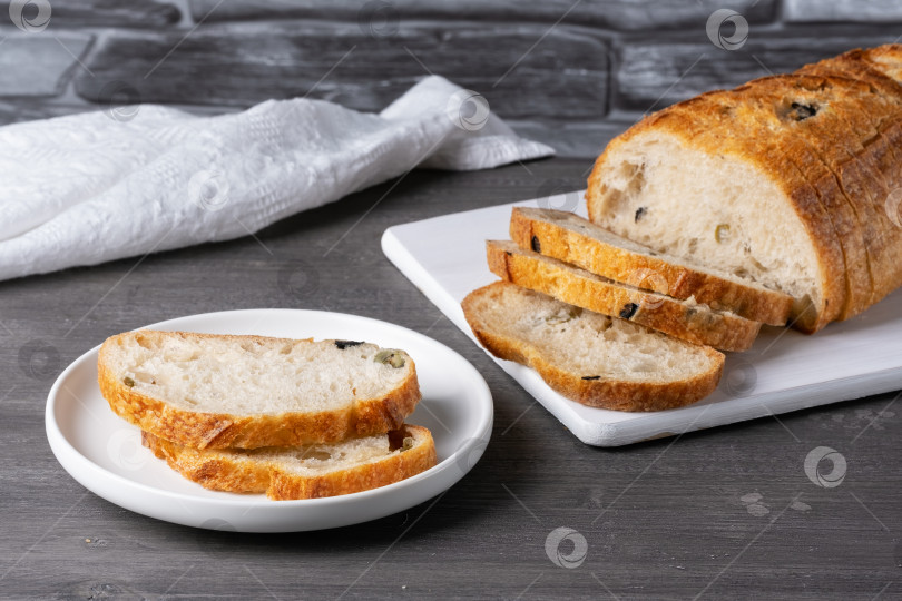 Скачать Хлеб с оливками на белой разделочной доске на сером столе фотосток Ozero