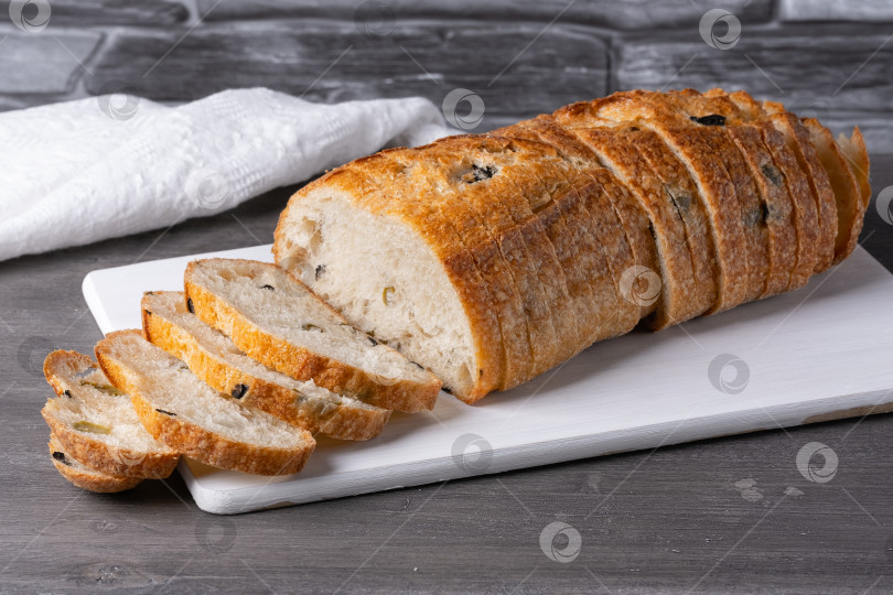 Скачать Хлеб с оливками на белой разделочной доске на сером столе фотосток Ozero