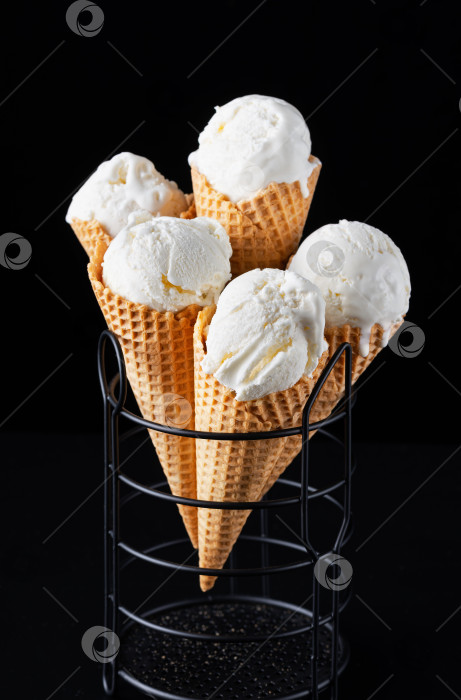 Скачать Крупным планом видно вкусное ванильное мороженое в хрустящем вафельном рожке на черном фоне фотосток Ozero