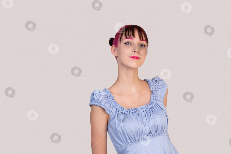 Скачать улыбающаяся девочка-подросток в голубом платье заглядывает в кадр на светлом фоне фотосток Ozero